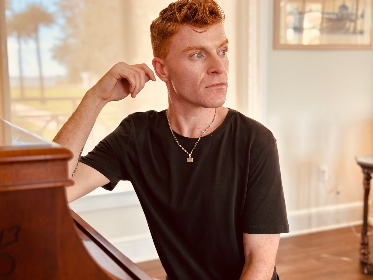 Weston Allen Kemp seated beside a piano for The Off-Central Players production of Nocturne