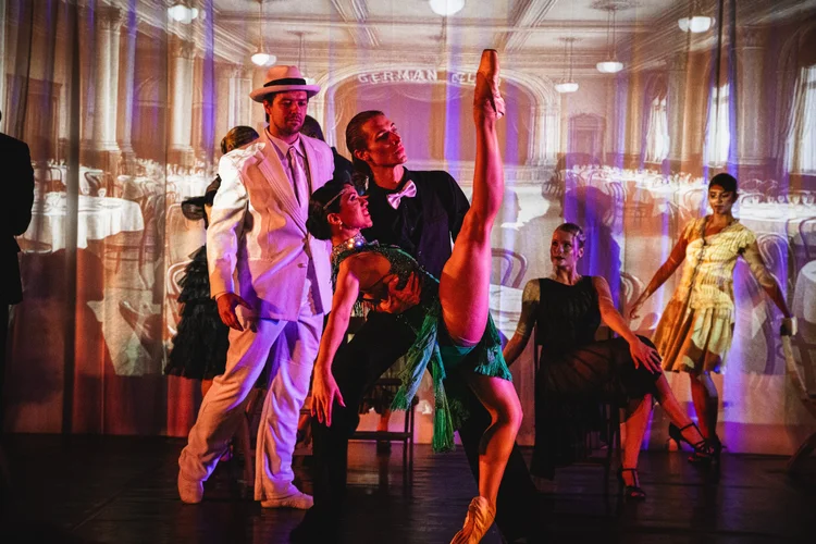 Dancers in 1920s dress perform against projected images of a historic Ybor City social club ballroom