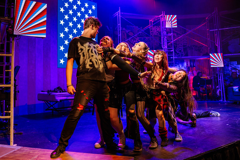 The ensemble reaches toward Johnny in a charged group number.
