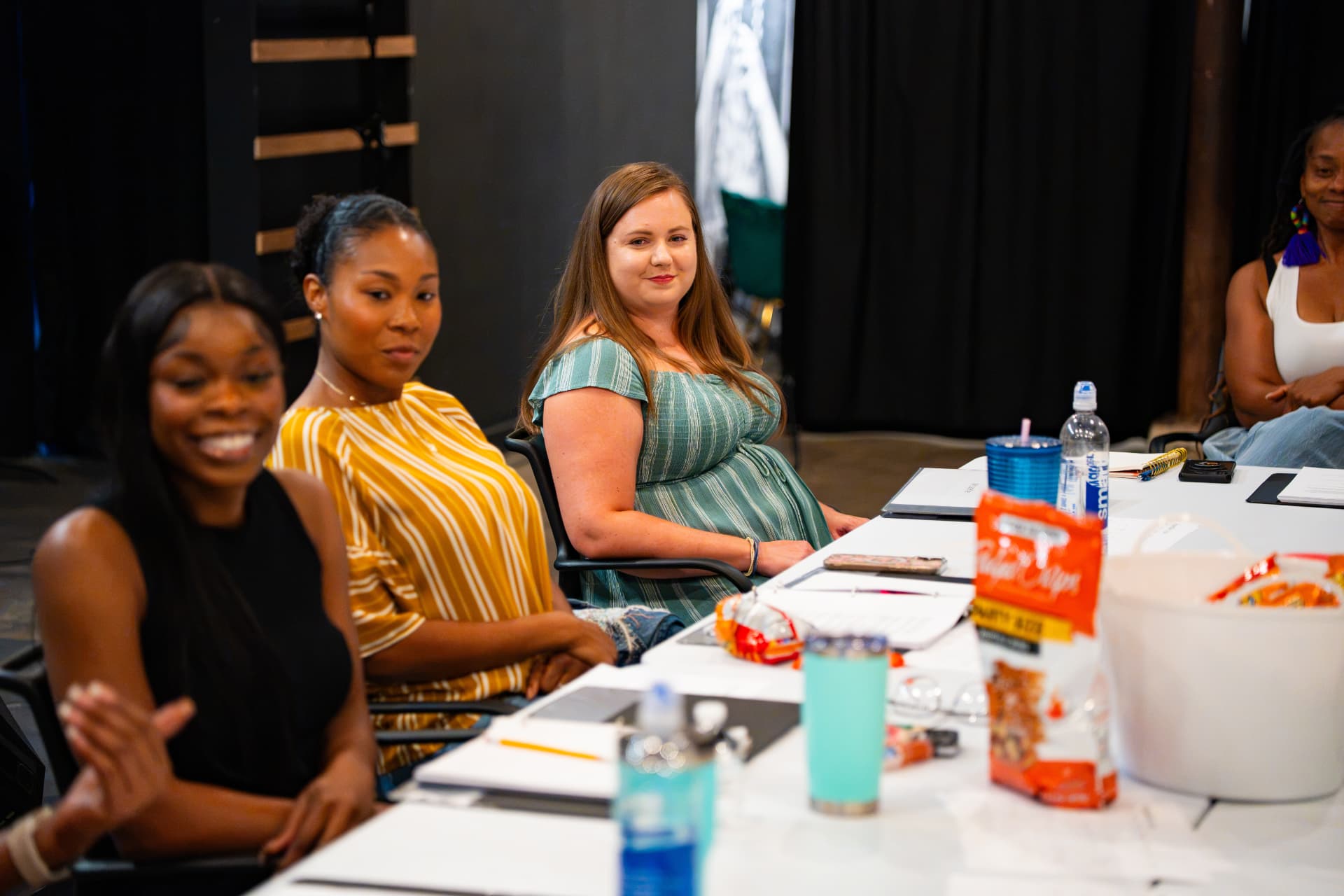 Cast members of The Wash listen and laugh during a rehearsal table session