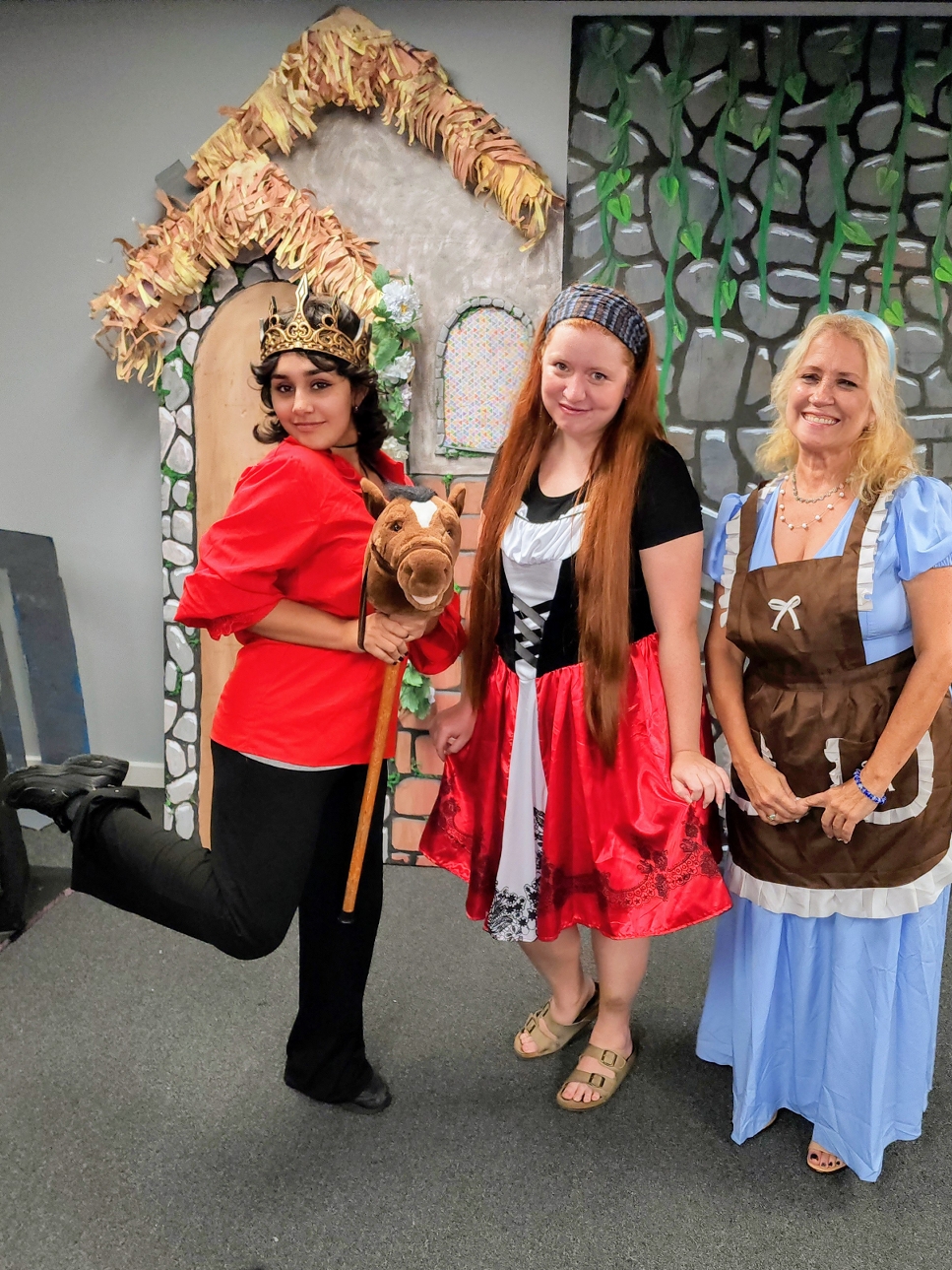Three performers in fairy-tale costumes with a hobby horse.