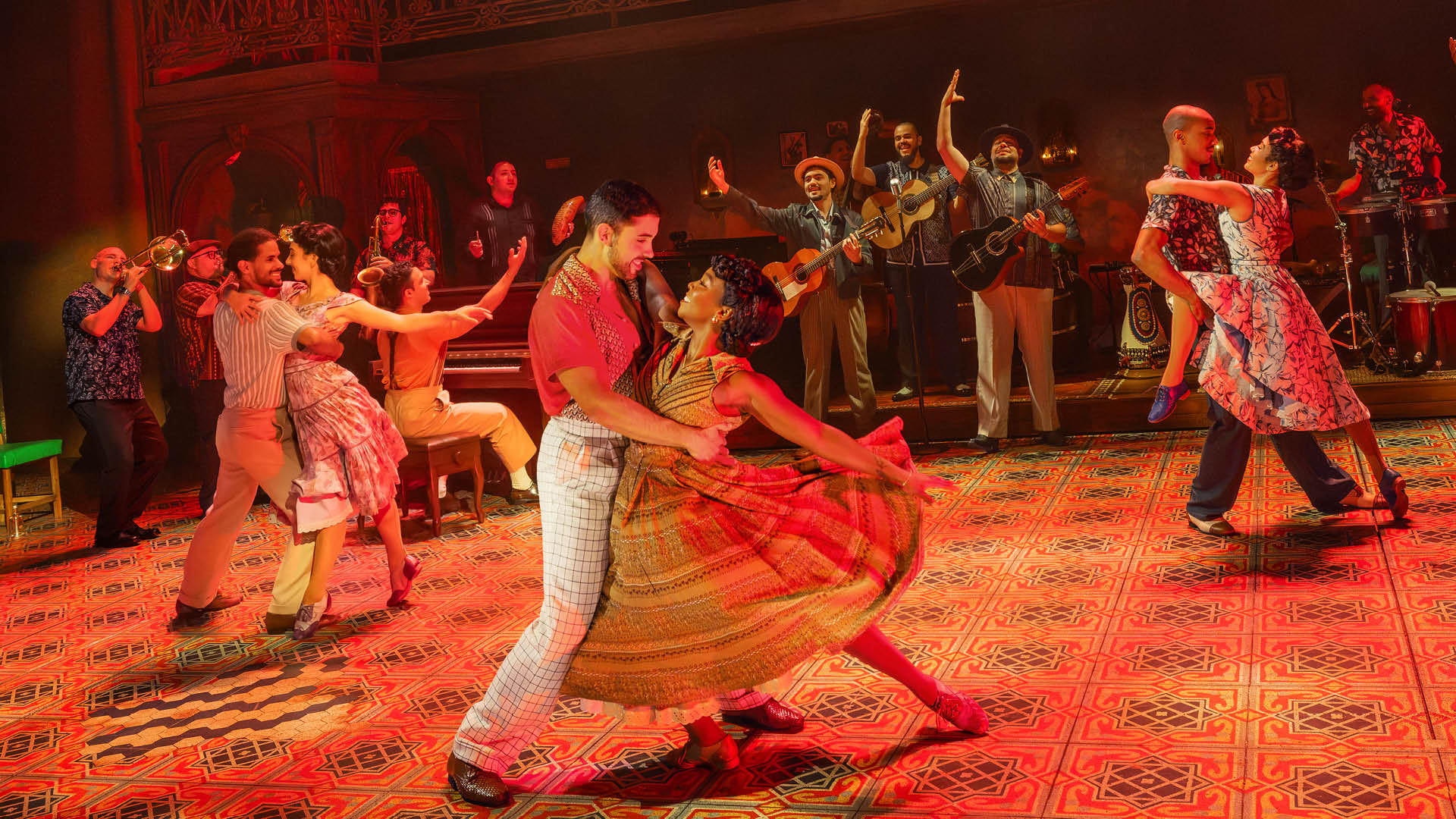 The company of the Buena Vista Social Club national tour dances on a red-tiled stage as the band plays behind them.