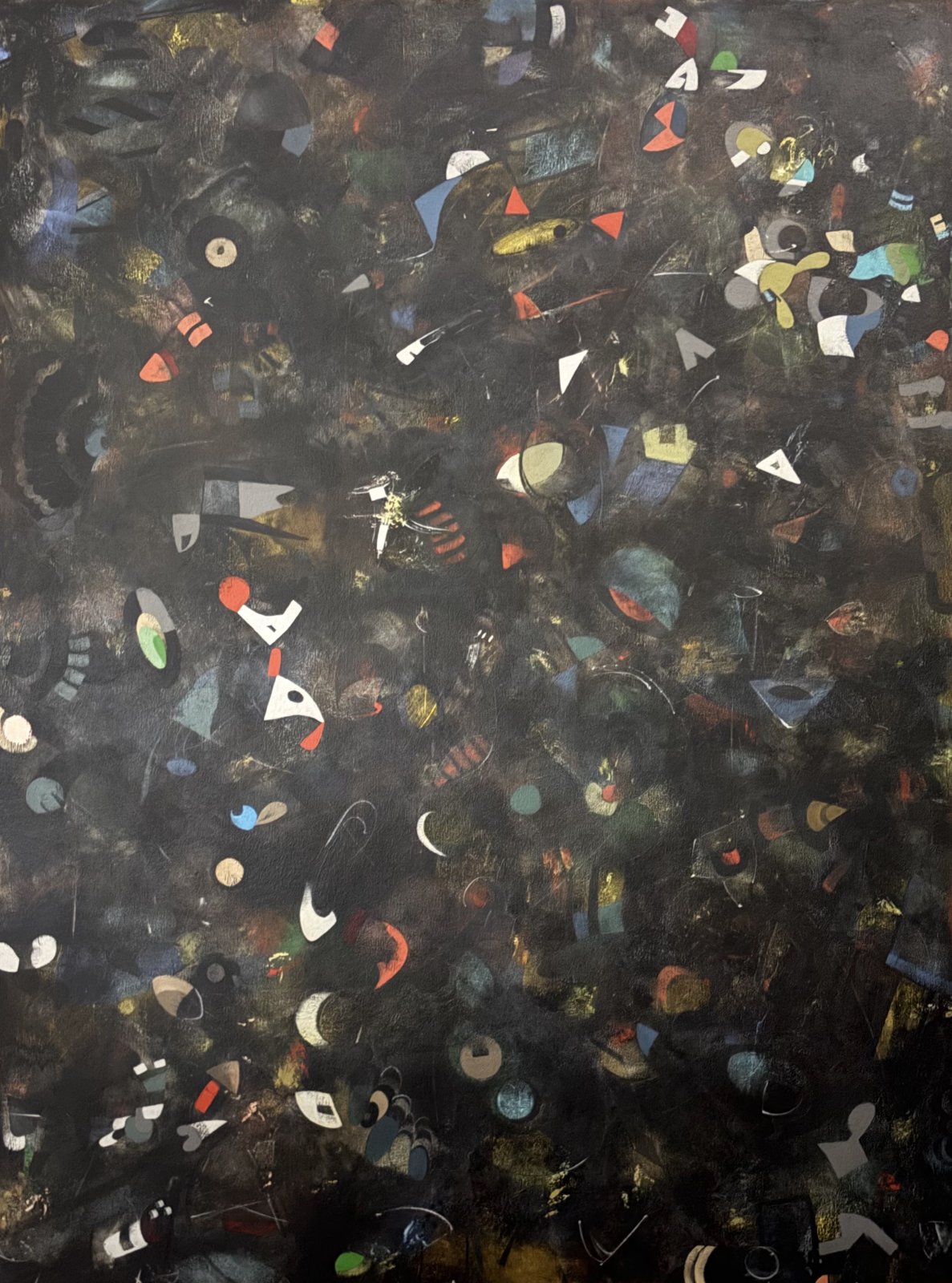 Small colored abstract shapes drift through a dark, layered background in Carla Poindexter’s If You Think About It, An Enfant Terrible Might Unscramble Your 86 Billion Neurons.